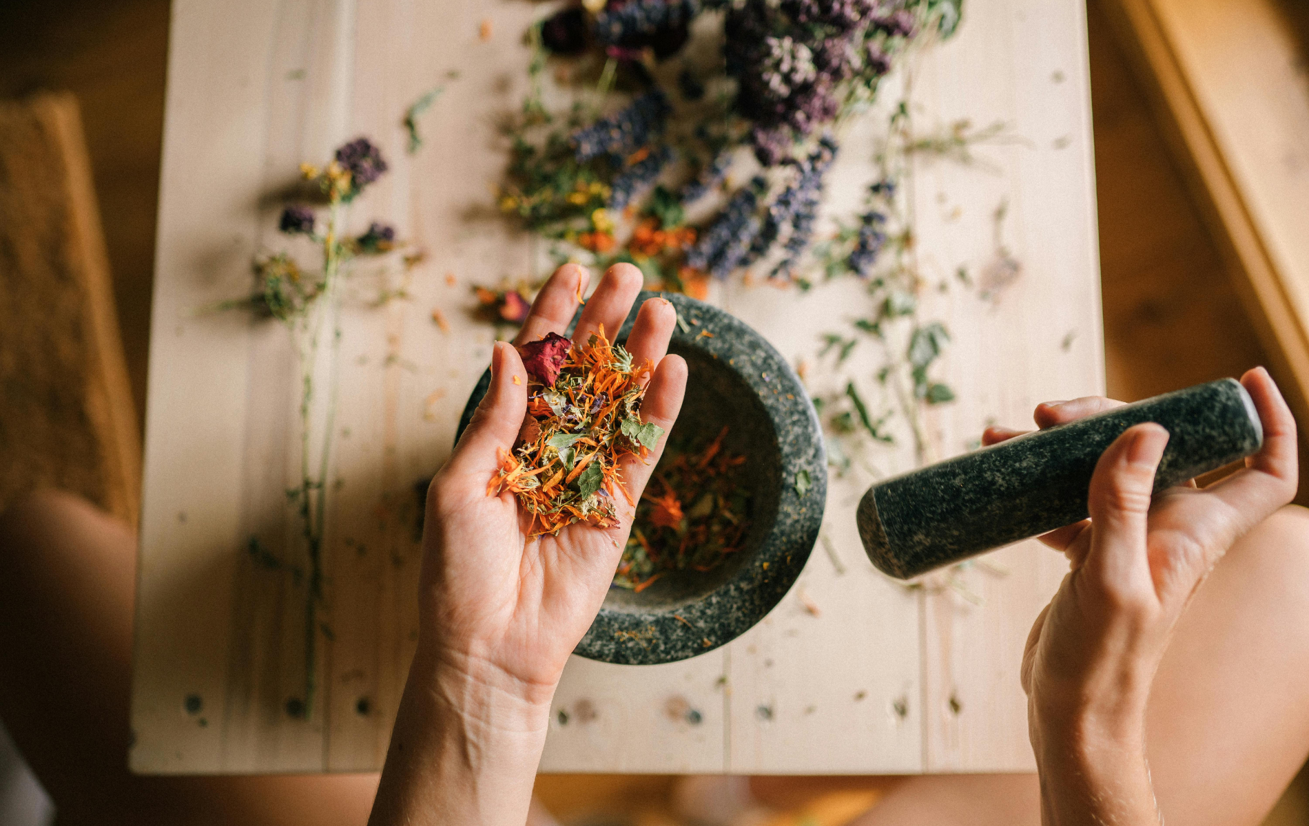 Hand using a marble mortar and pestle to grind herbs.